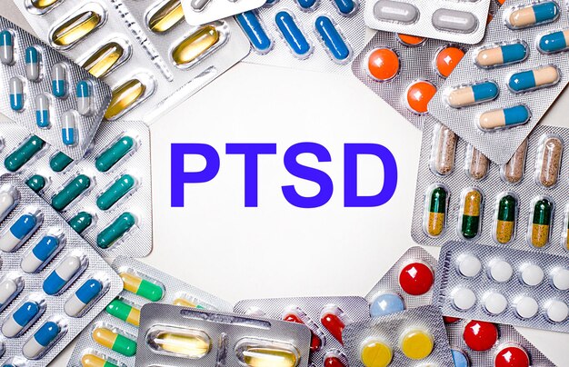 La parola PTSD è scritta su uno sfondo chiaro circondato da confezioni multicolori con pillole. Concetto medico