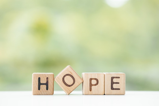 La parola speranza è scritta su cubi di legno su uno sfondo verde estivo Primo piano di elementi in legno
