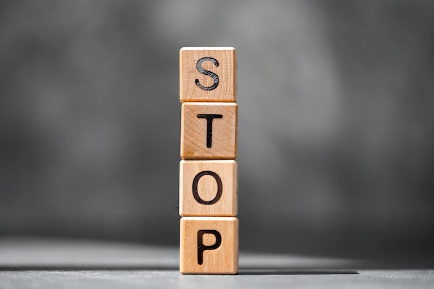 La parola STOP è fatta di blocchi di legno sul tavolo scuro