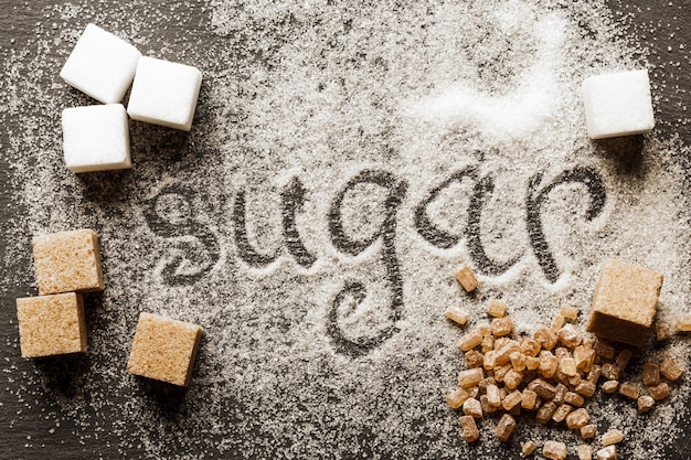 La parola zucchero scritto in una pila di zucchero semolato bianco