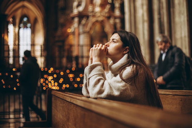 la parrocchiana della chiesa siede su una panchina con le mani giunte per la preghiera e prega di cuore