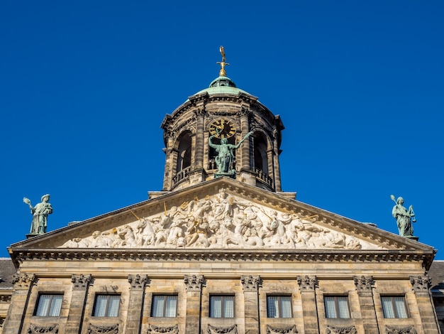 La parte anteriore del Palazzo Reale in Piazza Dam, Amsterdam, costruito come municipio durante l'età dell'oro olandese nel diciassettesimo secolo, sotto il cielo blu