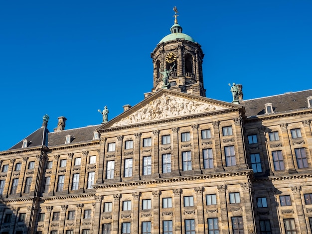 La parte anteriore del Palazzo Reale in Piazza Dam, Amsterdam, costruito come municipio durante l'età dell'oro olandese nel diciassettesimo secolo, sotto il cielo blu