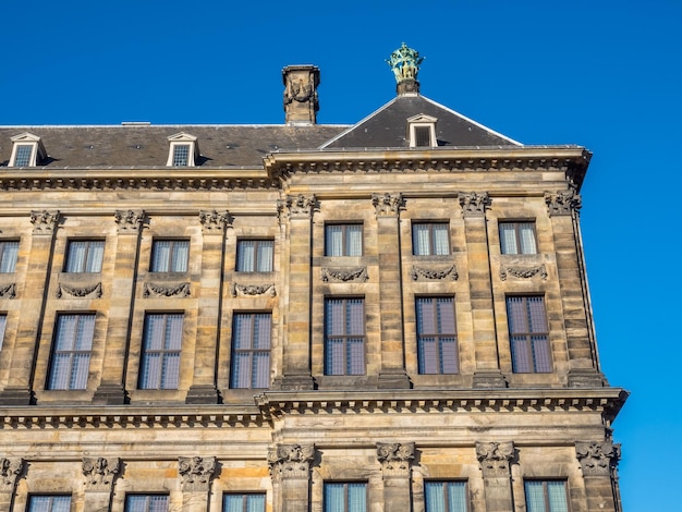 La parte anteriore del Palazzo Reale in Piazza Dam, Amsterdam, costruito come municipio durante l'età dell'oro olandese nel diciassettesimo secolo, sotto il cielo blu