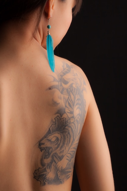 La parte posteriore di una ragazza adolescente con un tatuaggio di tigre sulla schiena destra