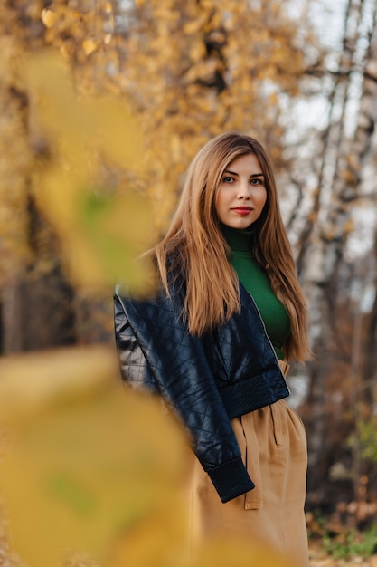 La passeggiata alla moda accogliente della ragazza al parco di autunno