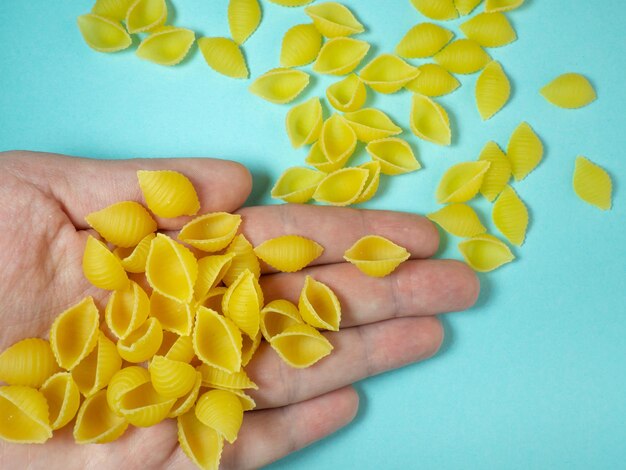 La pasta a forma di conchiglia cade dalla tua mano Cibo italiano La cucina dei popoli del mondo semola di grano duro