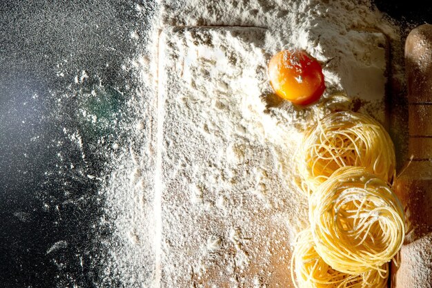 La pasta appena cotta giace su una superficie scura spolverata di farina Pasta italiana Tagliatelle Pasta cruda Ricetta della pasta italiana Vista dall'alto dello spazio di copia