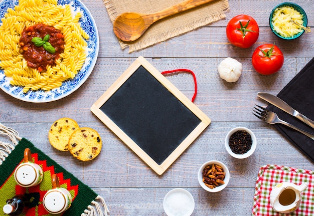 La pasta di Fusilli con la salsa di pomodori pomodori la cipolla ha asciugato l'aglio ha asciugato il pepe e l'olio d'oliva delle olive della paprica su un fondo di legno.