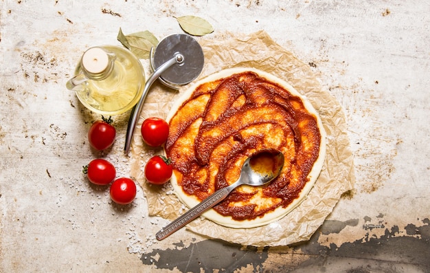 La pasta per pizza stesa con pomodori, concentrato di pomodoro e olio d'oliva.