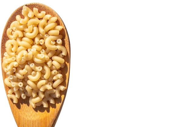 La pasta secca si trova in un cucchiaio di legno su uno sfondo bianco