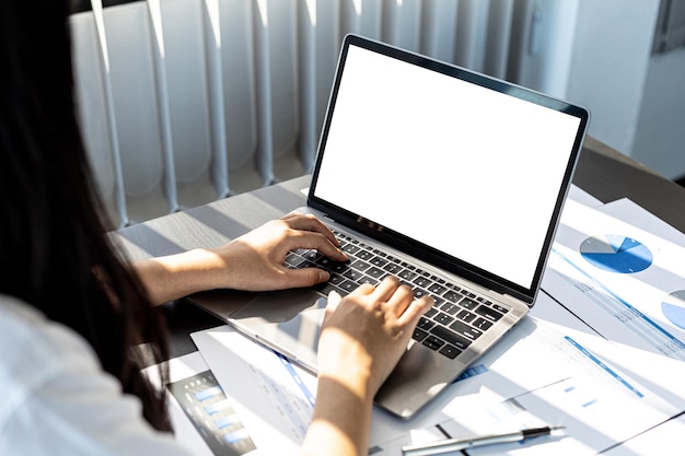 La persona che digita sulla tastiera del laptop, sullo schermo del laptop sfondo bianco vuoto per l'illustrazione, lo schermo mockup per ulteriori modifiche può essere utilizzato per una varietà di attività. copia spazio.