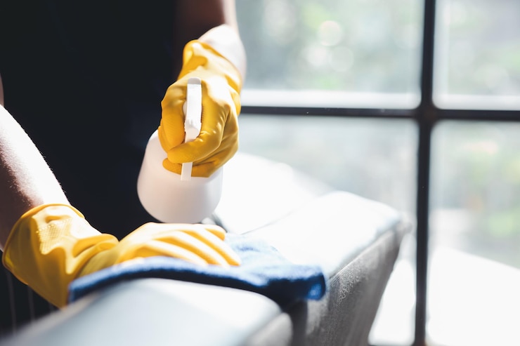 Foto la persona che pulisce la stanza il personale addetto alle pulizie usa un panno e spruzza disinfettante per pulire i divani nell'ufficio dell'azienda personale addetto alle pulizie mantenimento della pulizia nell'organizzazione