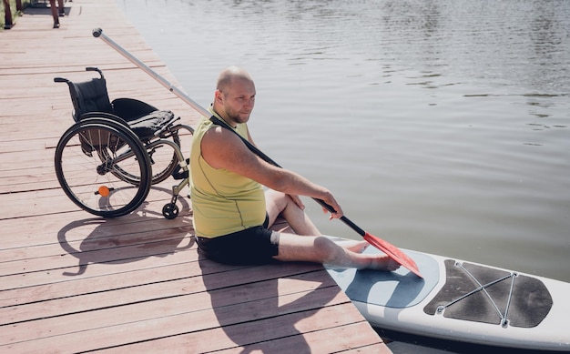 La persona con disabilità fisica su sedia a rotelle sarà guidata su una tavola sup