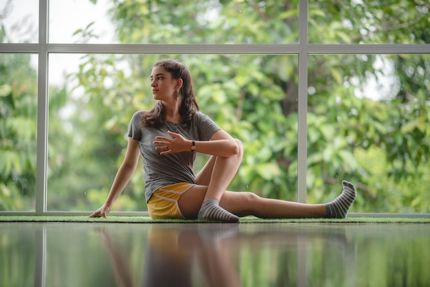 La persona della giovane donna sta imparando lo yoga a casa utilizzando video di formazione online sexy ragazza carina si rilassa con lo sport e il fitness a distanza esercizio stile di vita indoor casa isolata quarantena a casa concetto