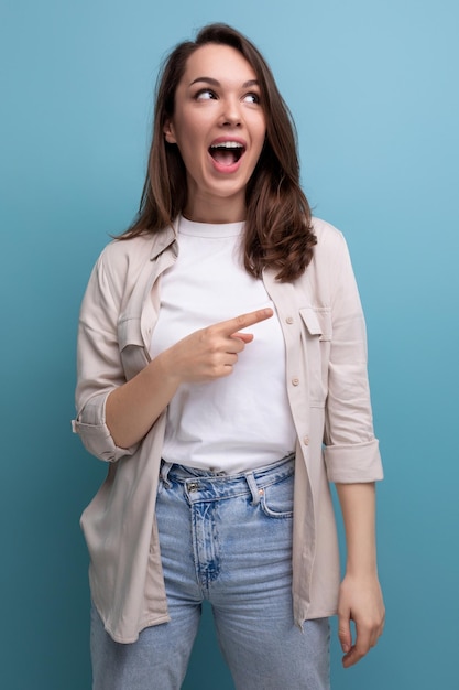 La persona femminile emotiva sorpresa di un anno del brunette vestita in una camicia e nei jeans distoglie lo sguardo su a