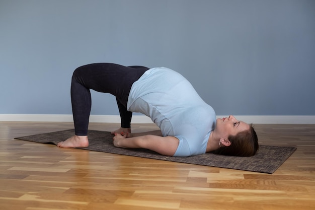 La persona in forma felice incinta gode della pratica dello yoga a casa.