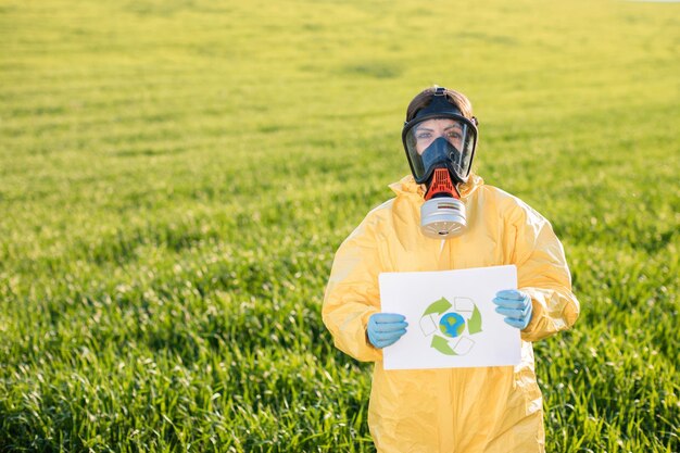 La persona in tuta e maschera antigas tiene in mano un foglio di carta con l'esclamazione Save the Planet