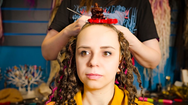La persona irriconoscibile fa l'acconciatura per la giovane donna nel parrucchiere professionista del salone che fa i capelli