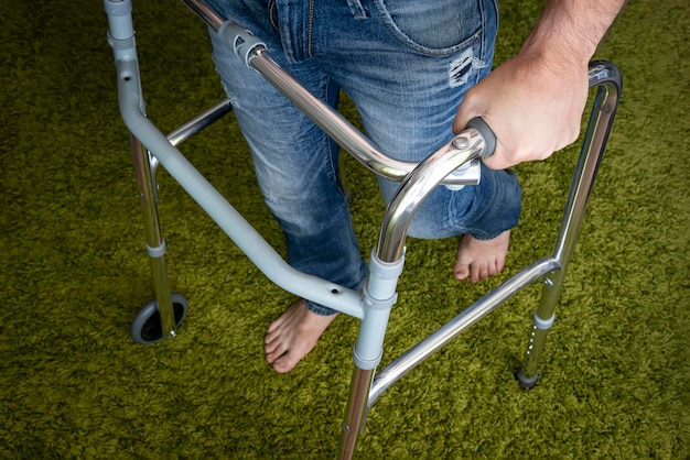 La persona malata cammina con l'aiuto di dispositivi speciali per la riabilitazione Walkers per la riabilitazione degli adulti dopo una gamba rotta o ictus