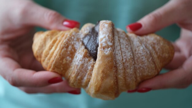 La persona tiene il croissant saporito fresco con il cioccolato