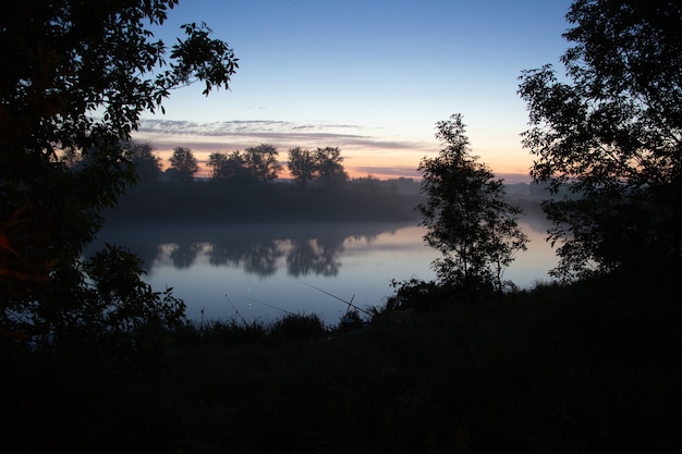 La pesca nel lago nebbioso al mattino presto appena prima dell'alba.