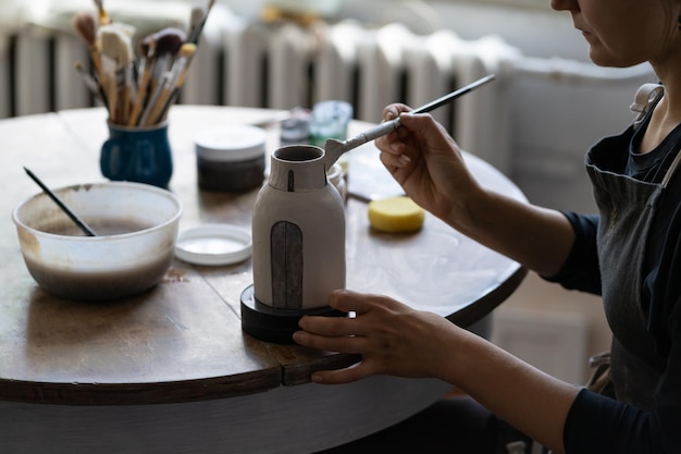 La piccola azienda di ceramiche proprietaria di una donna professionista tiene il pennello nelle mani e lavora una nave in miniatura