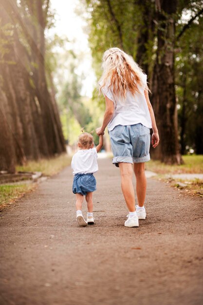 La piccola bella ragazza cammina nel parco con la sua mamma