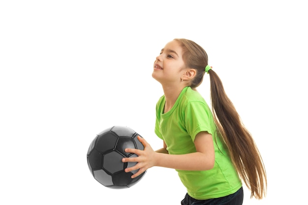La piccola donna gioca con un pallone da calcio isolato su bianco