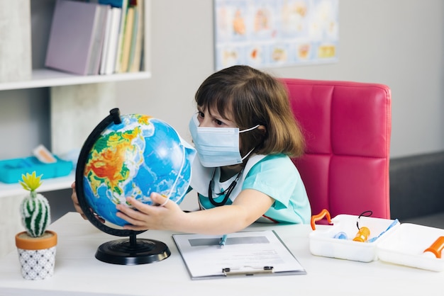 La piccola dottoressa carina mette una maschera sul globo del pianeta Terra salva le mani del pianeta terra