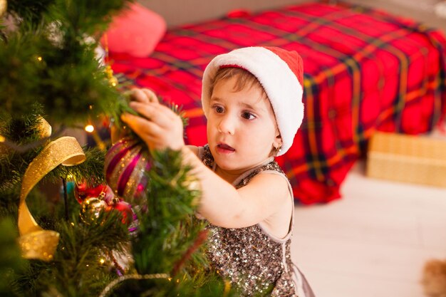 La piccola figlia decora il soggiorno per Natale. Buon Natale e buone feste