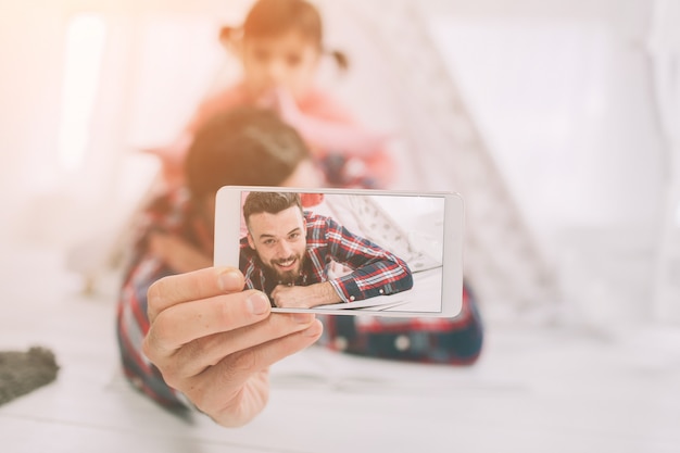 La piccola figlia sveglia e il suo bel giovane papà giocano insieme nella stanza del bambino. Papà e figlio trascorrono del tempo insieme seduti sul pavimento in camera da letto