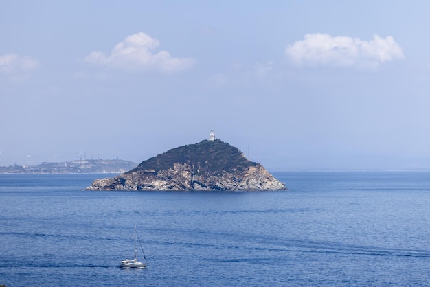 La piccola insenatura di Palmaiola ha scogliere rocciose e scoscese, faro di 105 m di altezza, arcipelago toscano, Italia