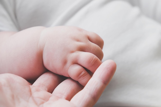 La piccola mano sveglia del neonato tiene le dita della madre