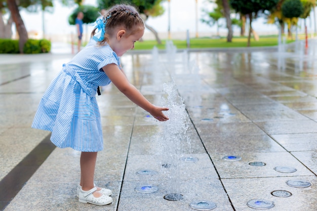 La piccola ragazza adorabile si diverte in fontana al giorno soleggiato caldo