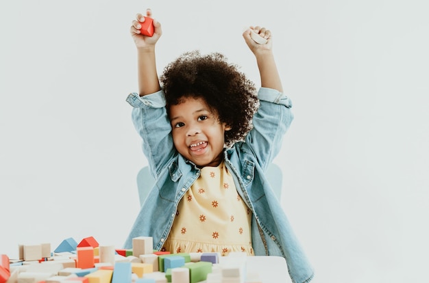 La piccola ragazza afroamericana carina si diverte a giocare con i blocchi giocattolo colorati sul tavolo in età prescolare Giocattolo educativo per bambini per la scuola materna o la scuola materna