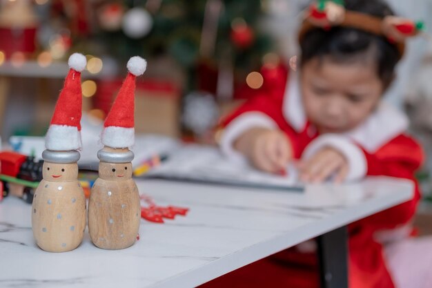 La piccola ragazza asiatica felice si diverte alla festa di Natale nel soggiorno con decorazioni a casa.