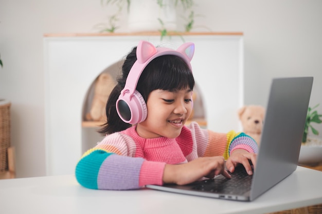 La piccola ragazza asiatica sorridente ha una lezione di videochiamata a distanza con l'insegnante che utilizza il laptop, distanza sociale durante l'isolamento di quarantena durante il Coronavirus