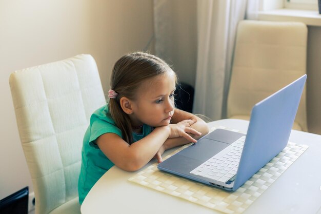 La piccola ragazza carina usa il laptop per fare una videochiamata