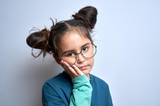 La piccola ragazza caucasica con l'espressione del viso sofferente tiene la guancia con la mano che tocca la bocca con il palmo isolato su sfondo bianco Mal di denti concetto di dolore dentale