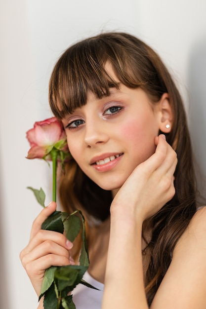 La piccola ragazza graziosa in rosa tiene il mazzo delle rose. Chiudere i fiori e il viso, piccola ballerina con un bouquet. Sorridi