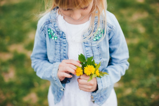 La piccola ragazza sta tenendo La piccola ragazza sta tenendo un mazzo di fiori gialli