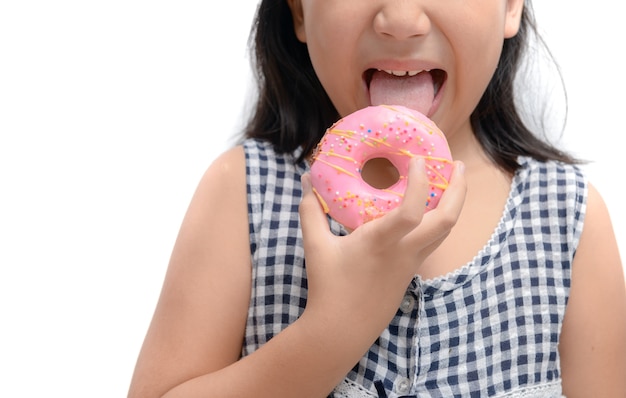 La piccola ragazza sveglia felice sta mangiando la ciambella isolata