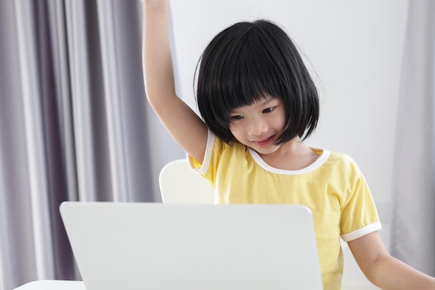 La piccola studentessa asiatica studia online utilizzando il computer portatile a casa