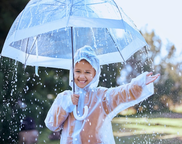 La pioggia offre grandi opportunità di divertimento Inquadratura di una bambina giocosamente in piedi sotto la pioggia con in mano l'ombrello