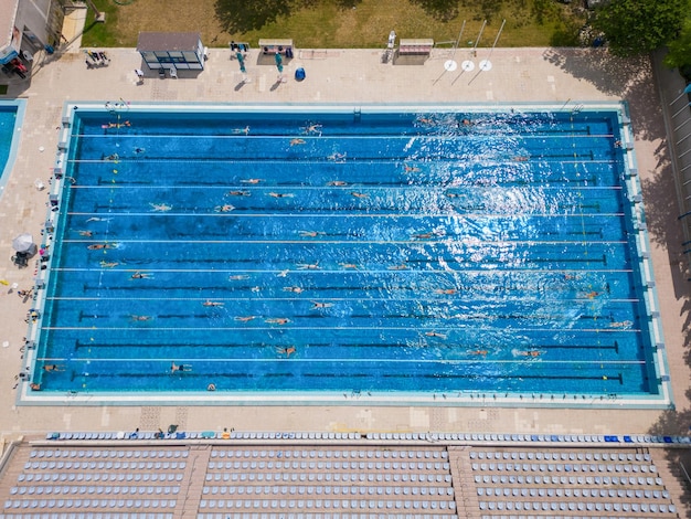 La piscina sportiva all'aperto brillava sotto il sole splendente mentre le persone nuotavano nelle sue invitanti acque