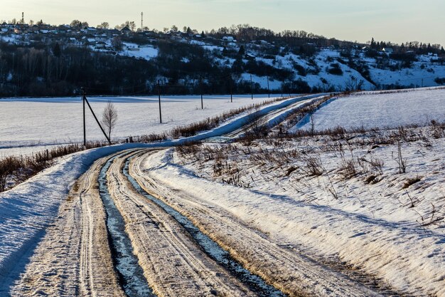 La pista stradale rustica in inverno scongela la luce del giorno senza nessuno