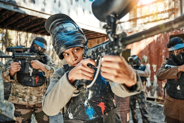 La pistola e la donna della squadra di paintball mirano a concentrarsi e sparare alla competizione di tiro al bersaglio o alla lotta o alla missione di un conflitto militare Il soldato o le persone del gruppo puntano l'arma nell'addestramento o nella battaglia della guerra di sopravvivenza