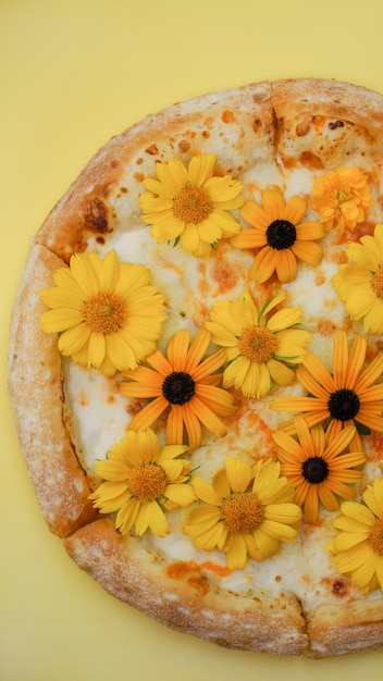 la pizza al formaggio con fiori si trova su un primo piano di sfondo semplice. concetto di cibo divertente