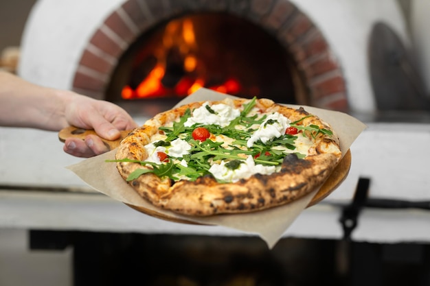 La pizza italiana pronta su un piatto di legno è pronta per essere servita nel ristorante